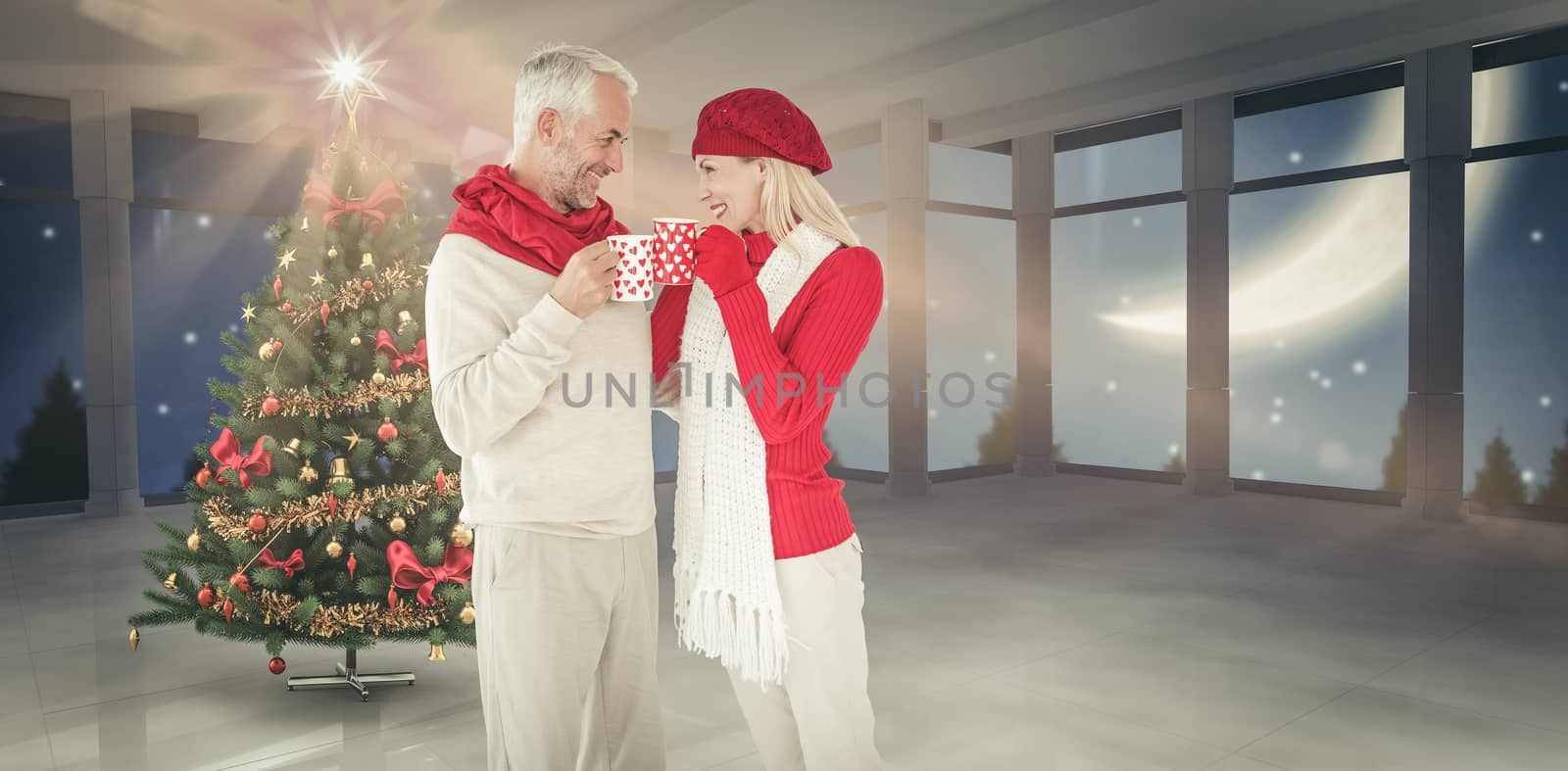 Happy winter couple with mugs against home with christmas tree