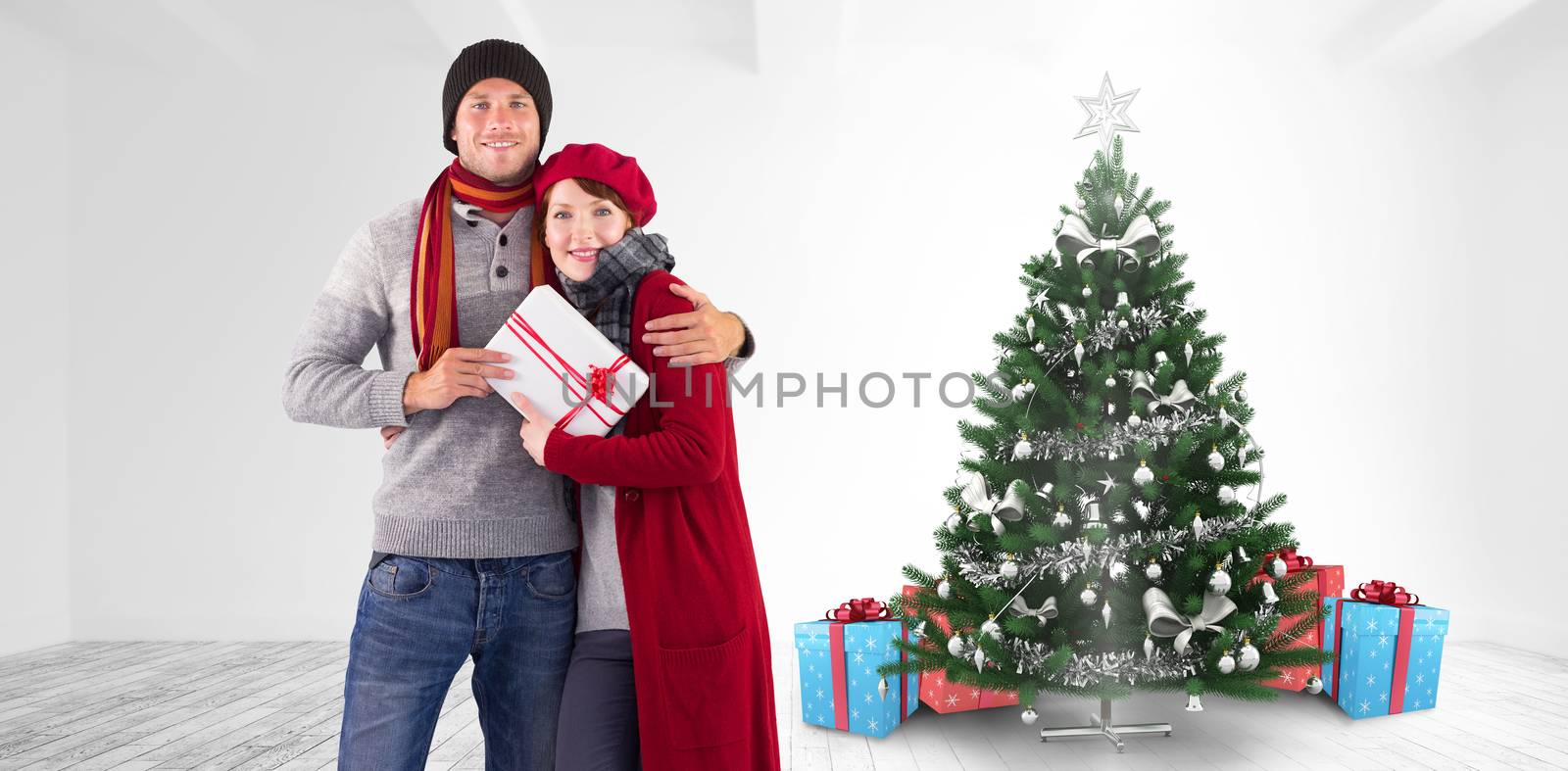 Couple smiling and holding gift against home with christmas tree