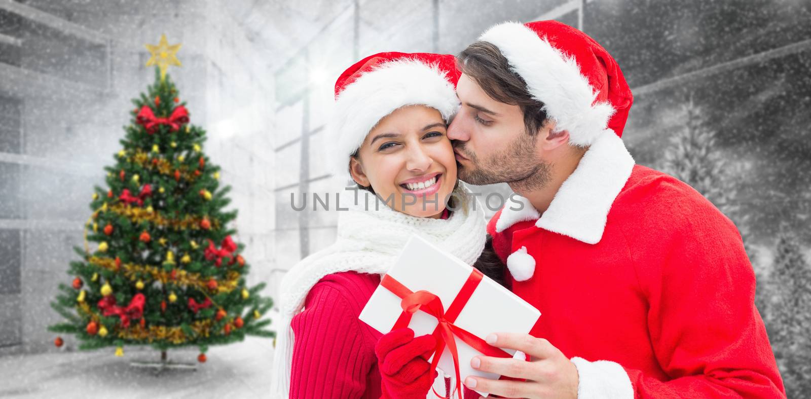 Festive young couple holding gift against home with christmas tree