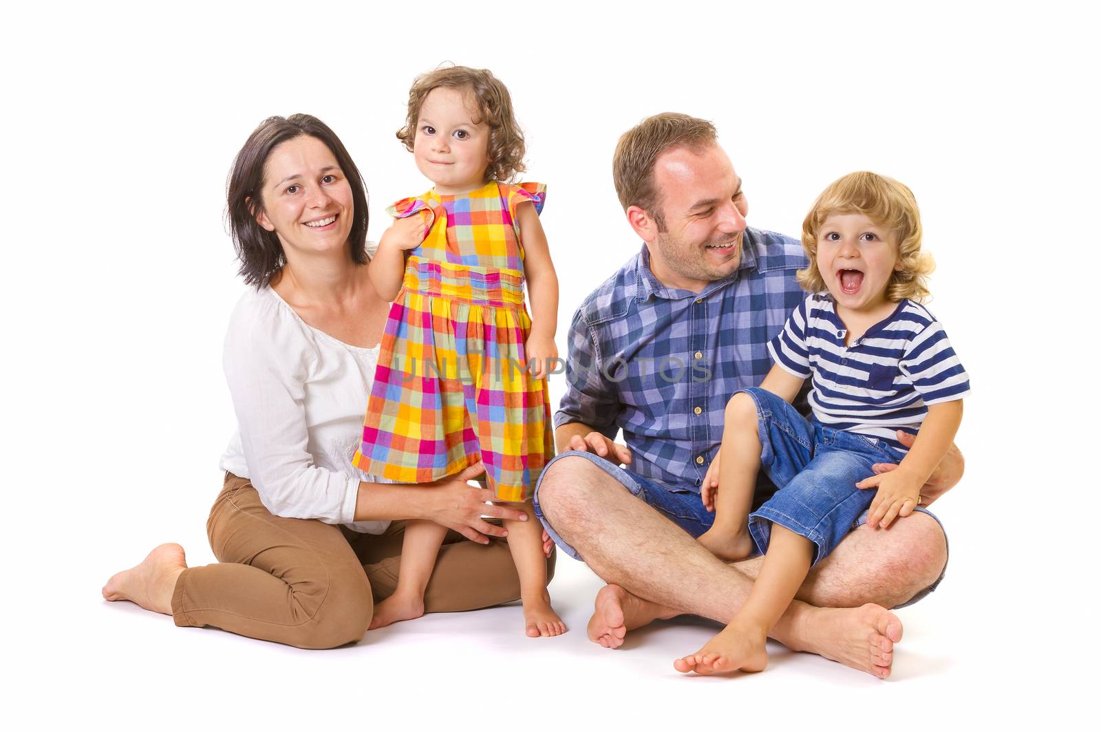 Happy family of four smiling while standing against white background.