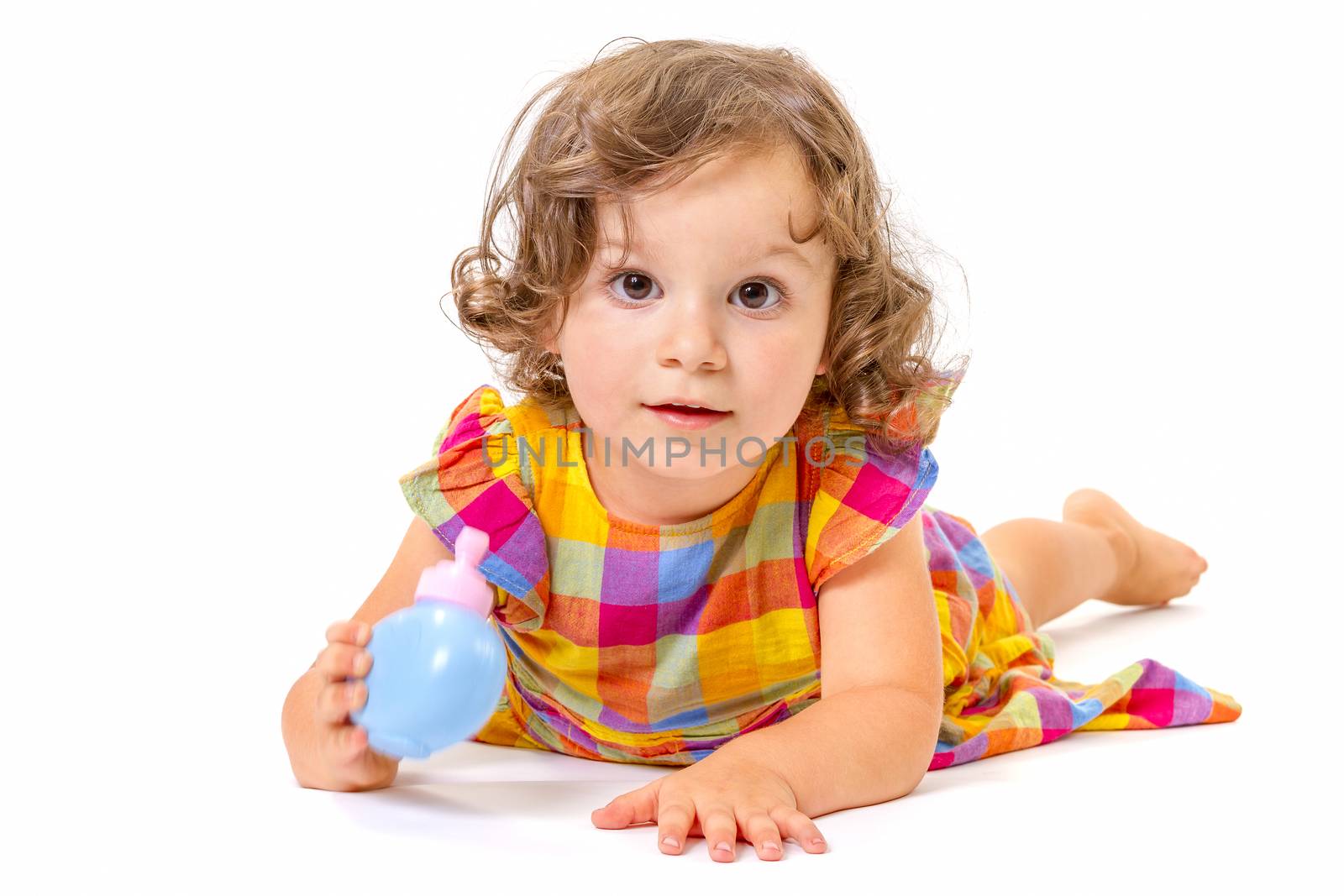 Cheerful little girl smiling at camera lying on white background.