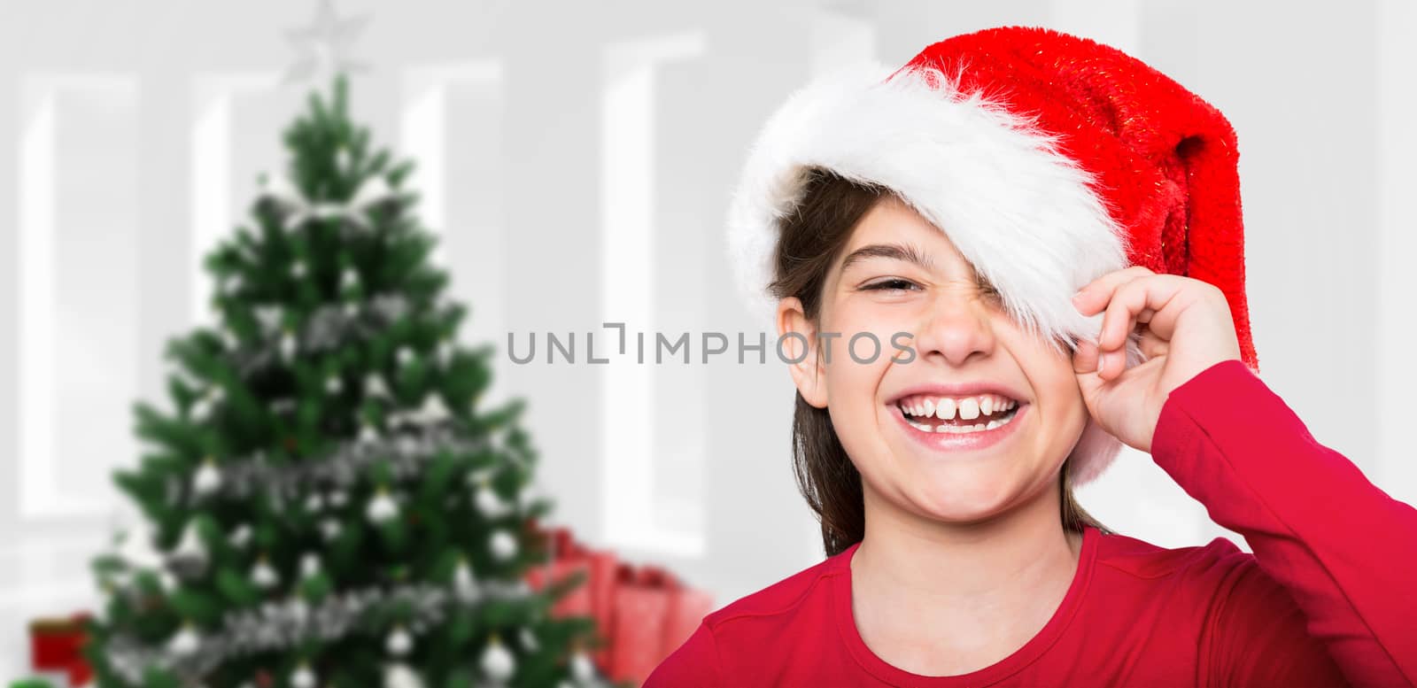 Festive little girl smiling at camera against home with christmas tree