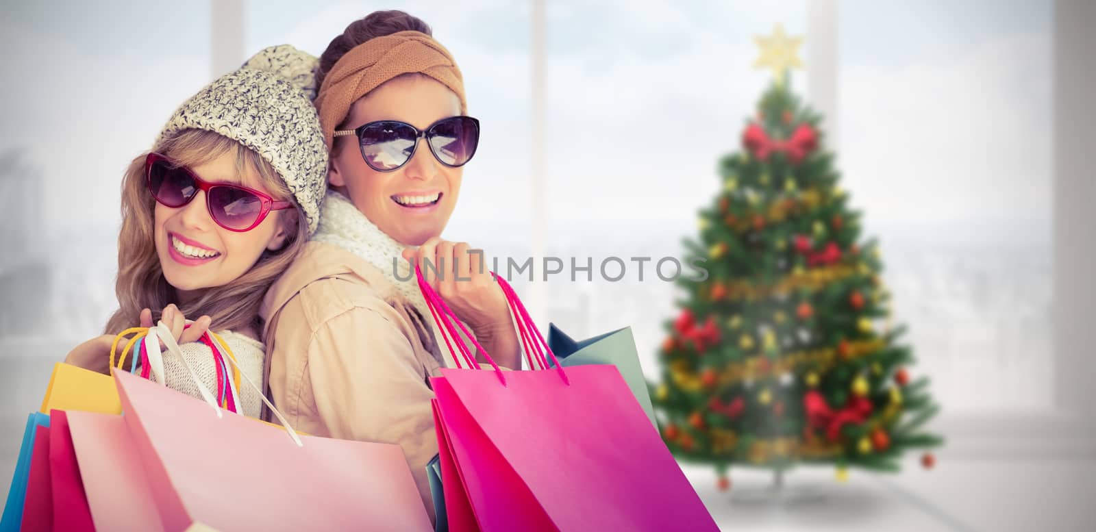 Beautiful women holding shopping bags looking at camera  against home with christmas tree