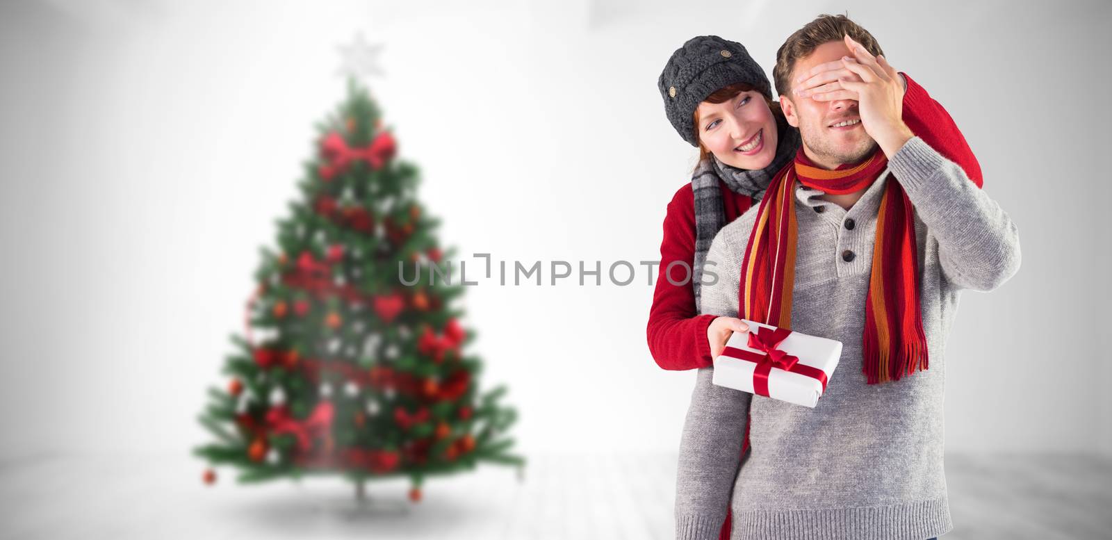 Woman giving man a present against home with christmas tree