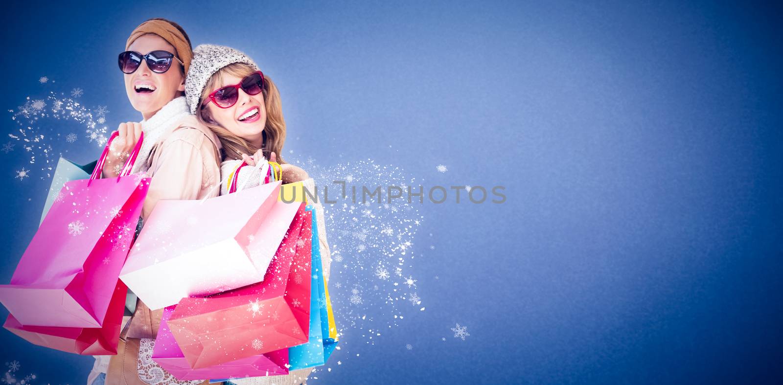 Beautiful women holding shopping bags looking at camera  against blue background