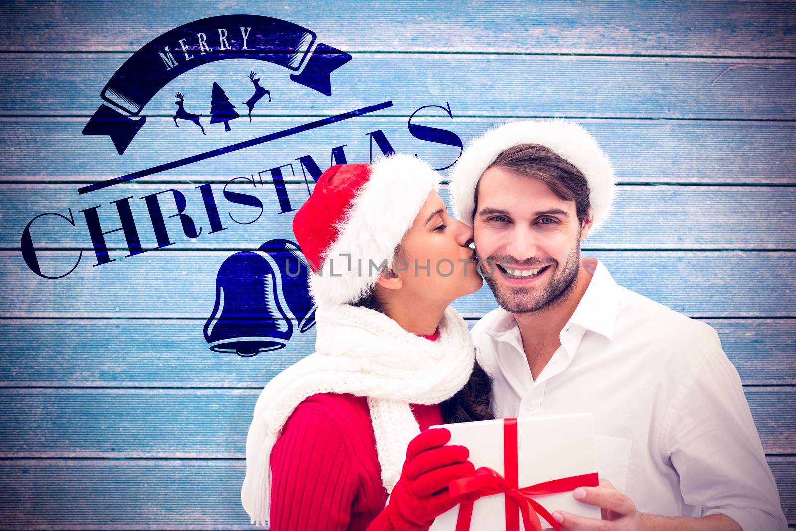 Festive young couple holding gift against wooden planks