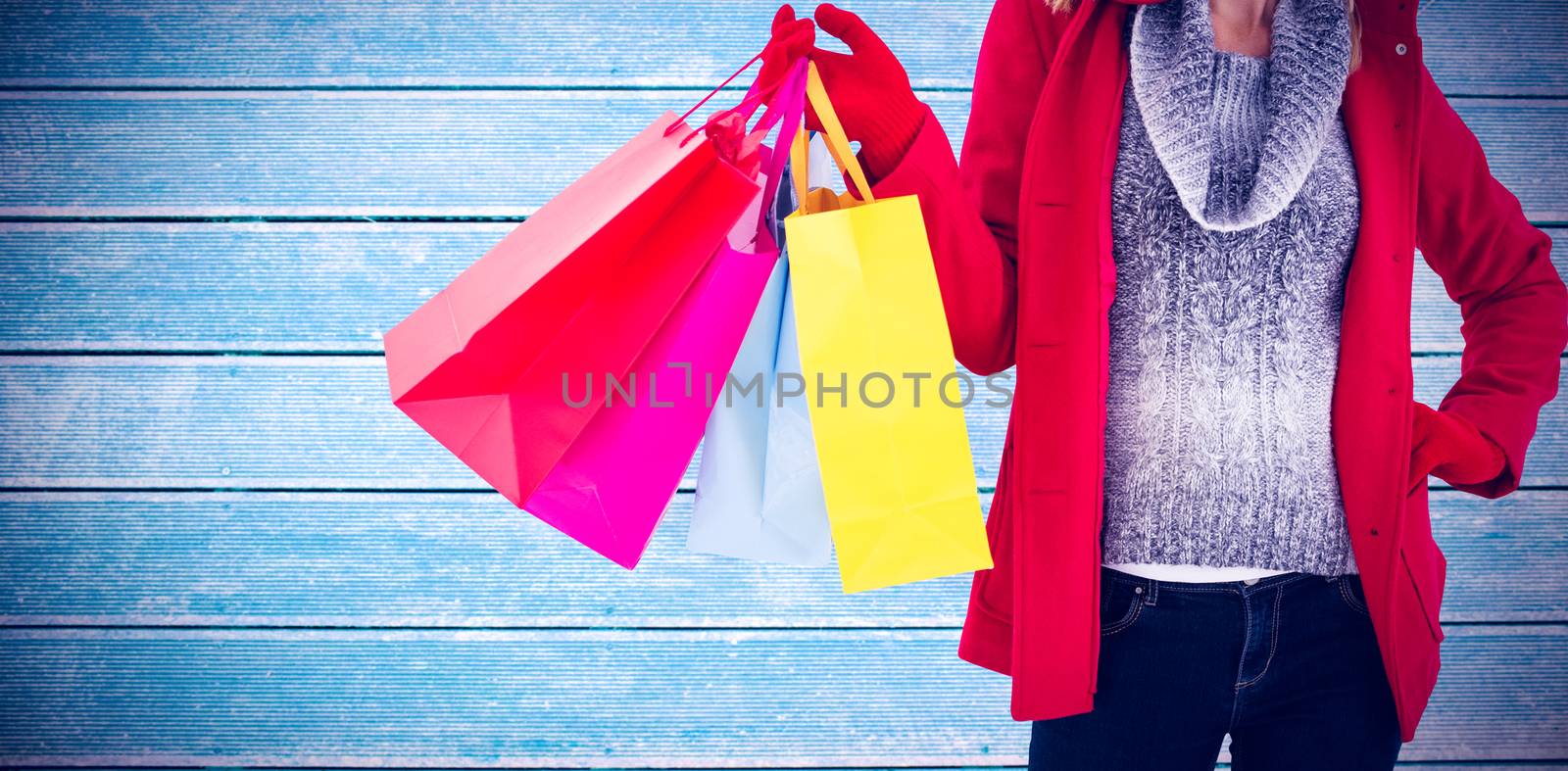 Blonde in winter clothes holding shopping bags against wooden planks
