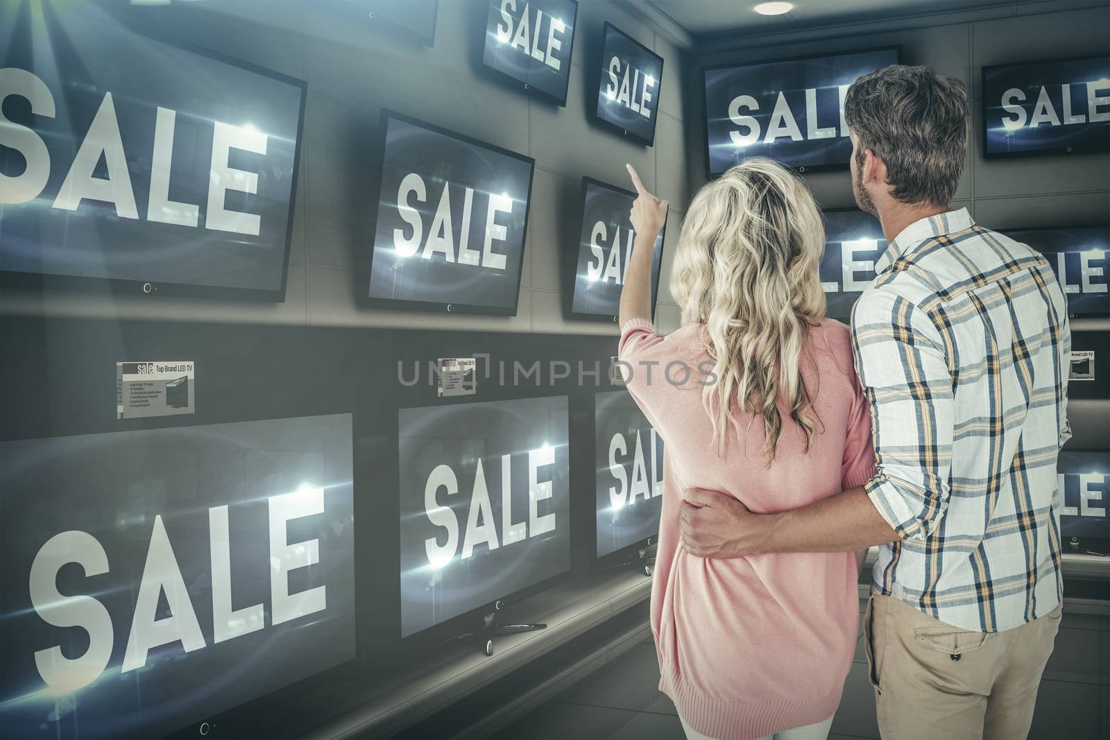Attractive couple standing and looking against sale ad on televisions
