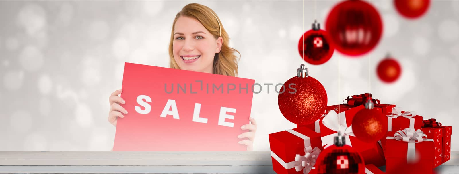 Cute blonde showing a red sale poster against painted blue wooden planks