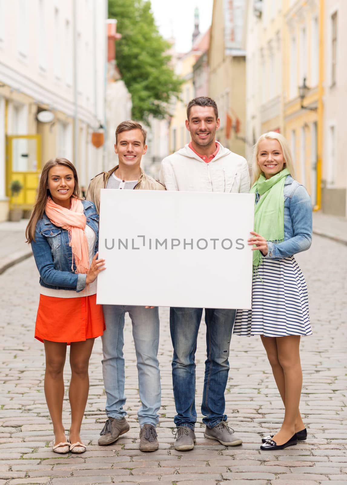 group of smiling friends with blank white board by dolgachov