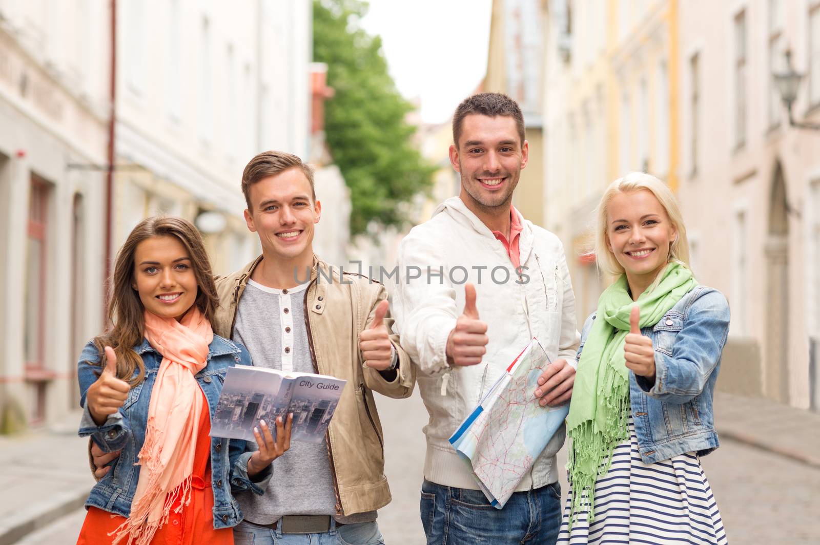 travel, vacation and friendship concept - group of smiling friends with city guide and map showing thumbs up in the city