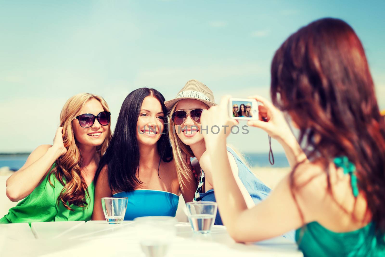 girls taking photo in cafe on the beach by dolgachov