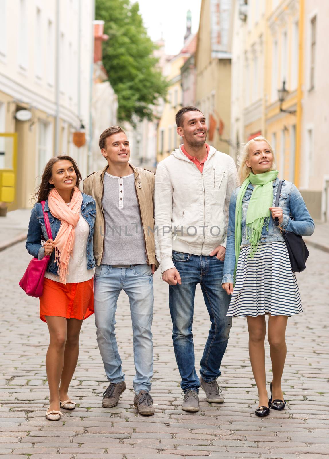 group of smiling friends walking in the city by dolgachov