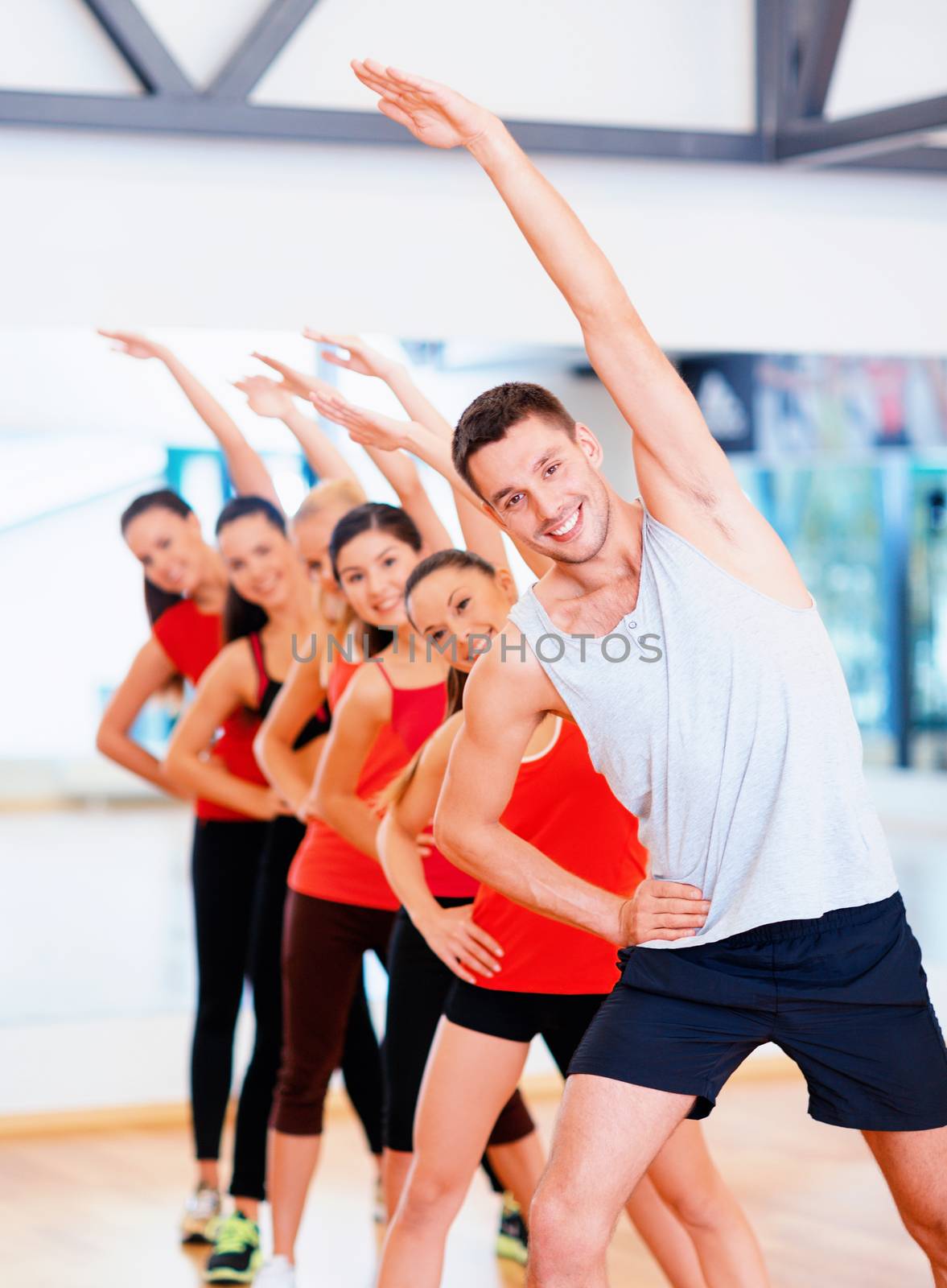 group of smiling people stretching in the gym by dolgachov