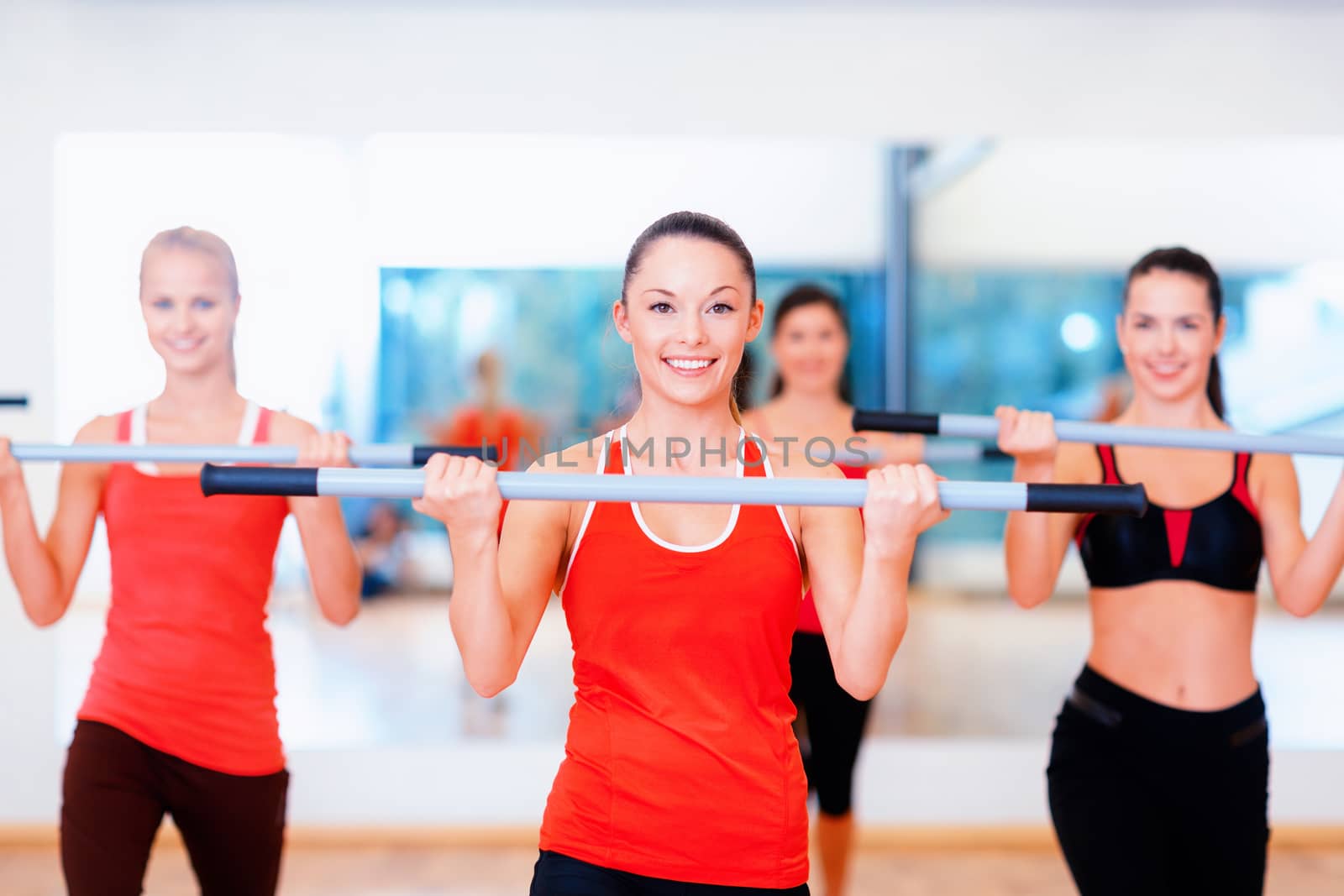 fitness, sport, training, gym and lifestyle concept - group of smiling people working out with barbells in the gym