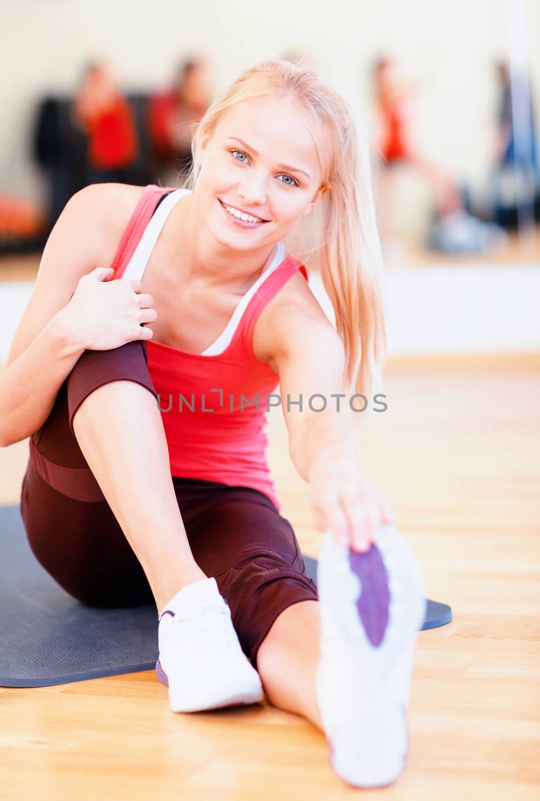 smiling woman stretching on mat in the gym by dolgachov
