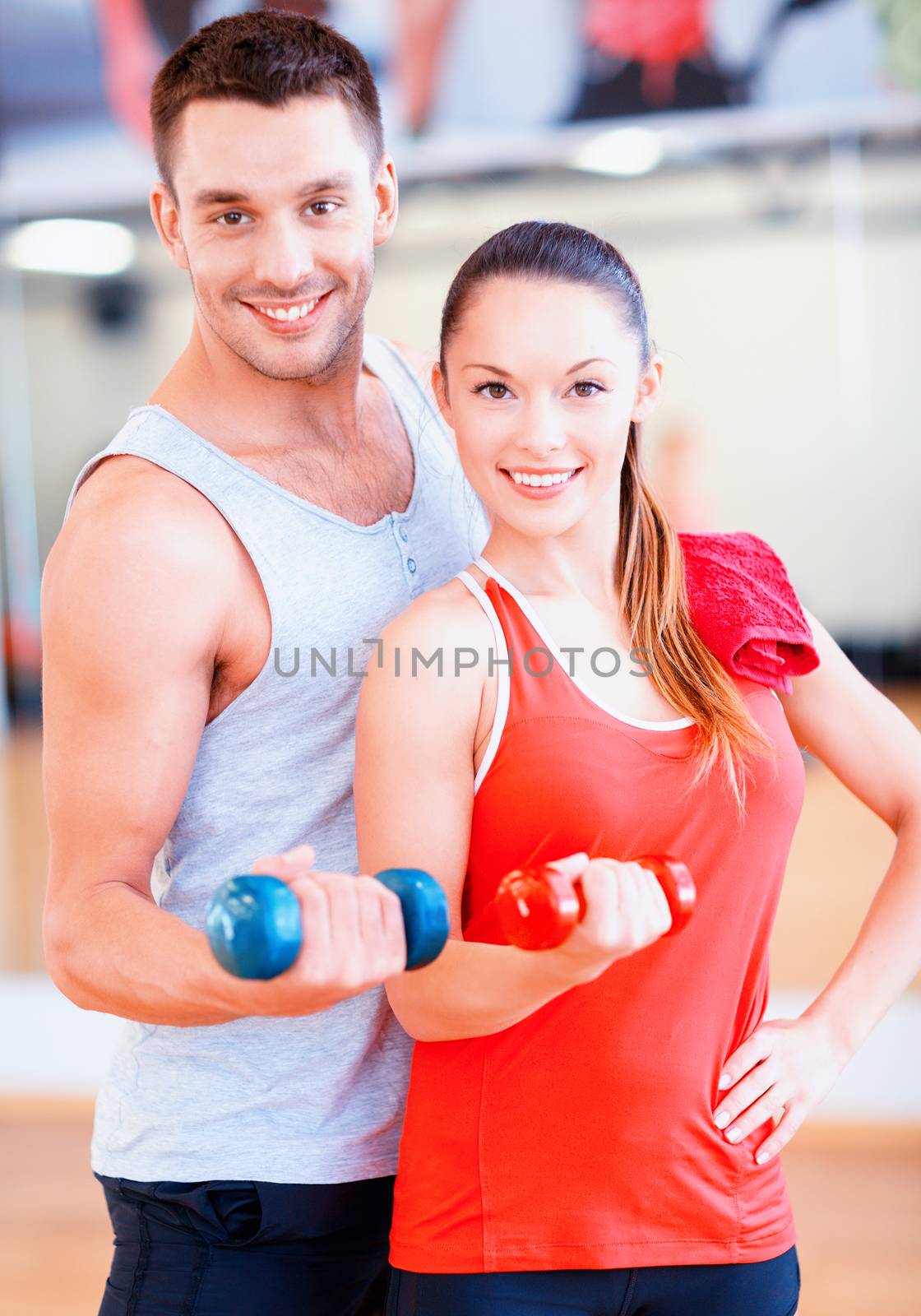 fitness, sport, training, gym and lifestyle concept - two smiling people working out with dumbbells in the gym