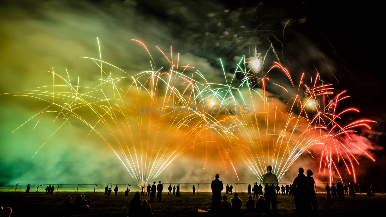 Colorful fireworks of various colors over night sky with spectators