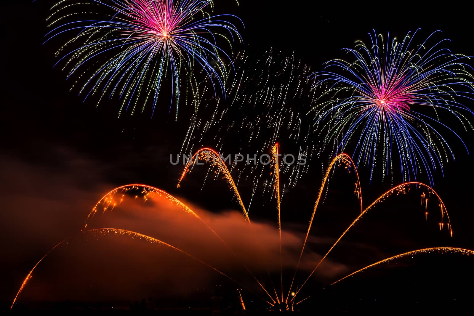 Colorful fireworks of various colors over night sky with spectators