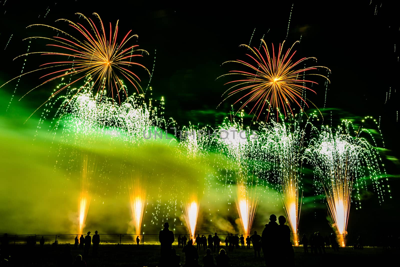 Colorful fireworks of various colors over night sky with spectators