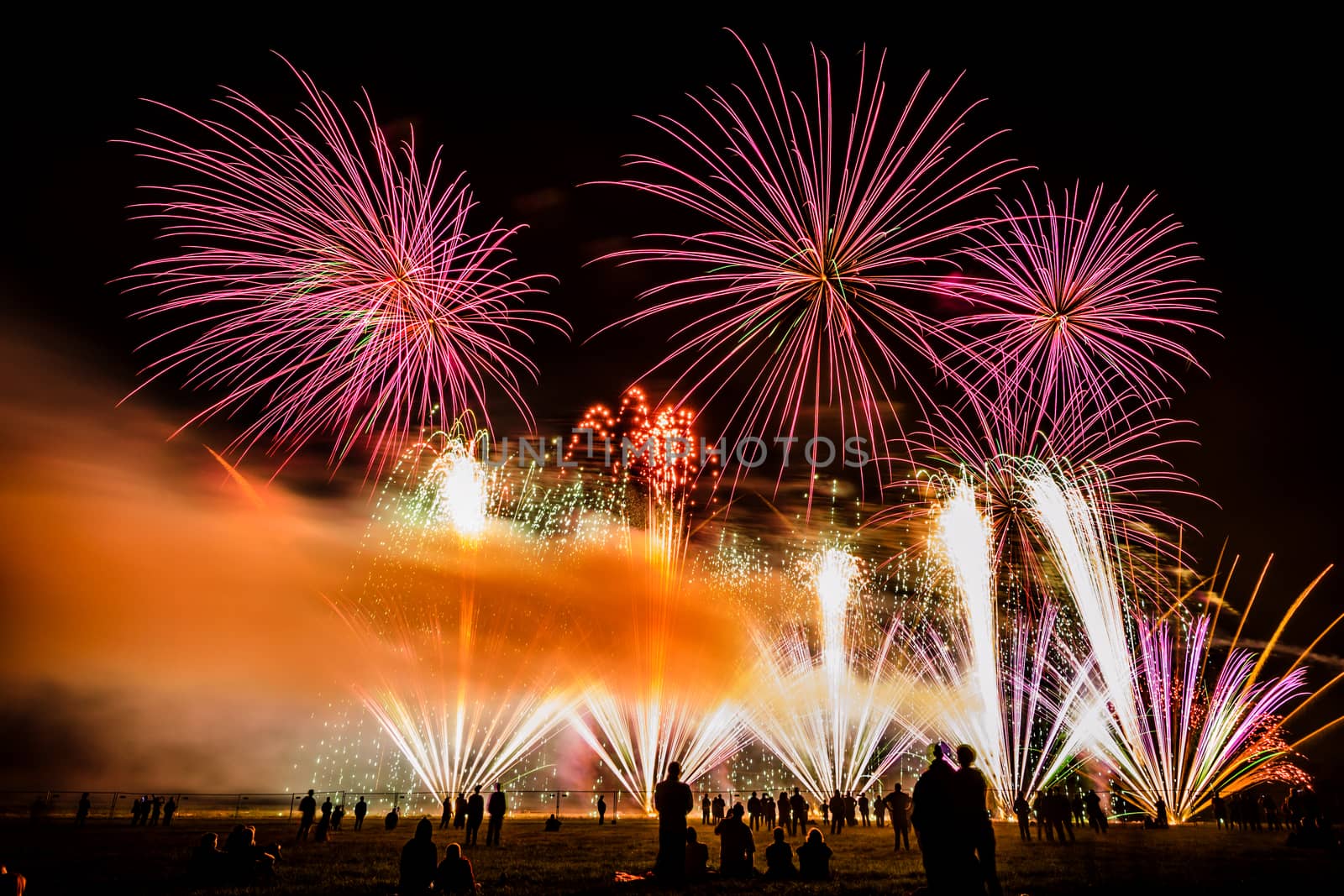 Colorful fireworks of various colors over night sky with spectators