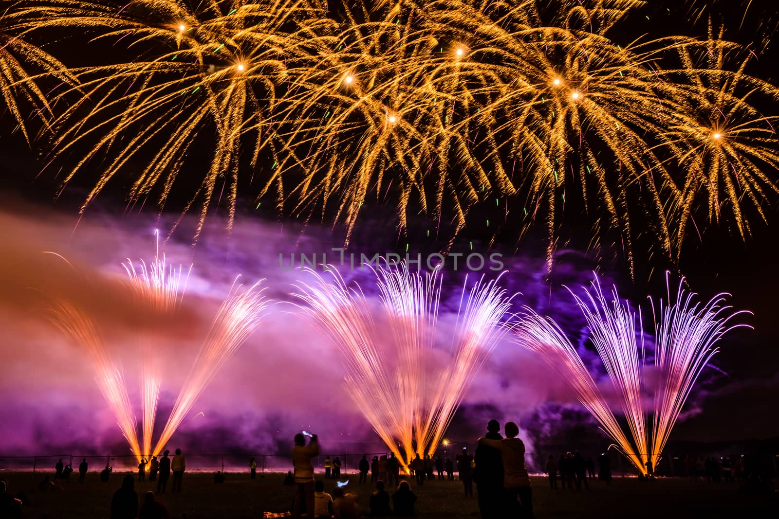 Colorful fireworks of various colors over night sky with spectators