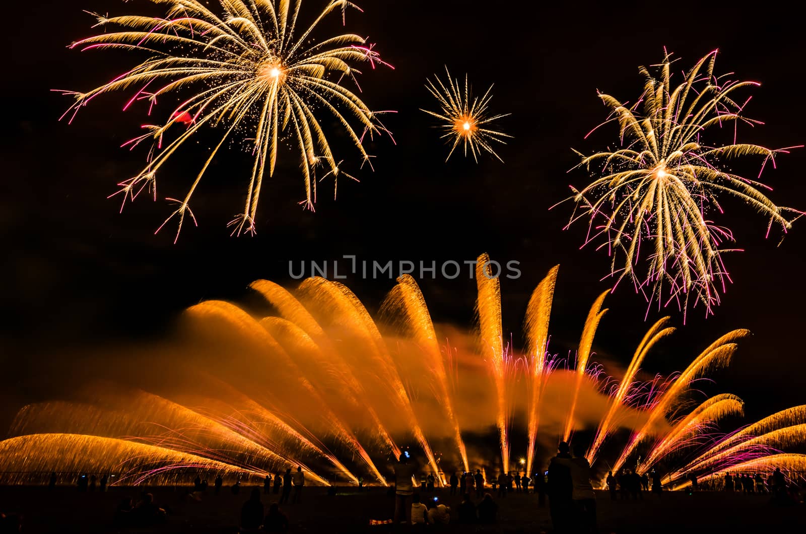 Colorful fireworks of various colors over night sky with spectators