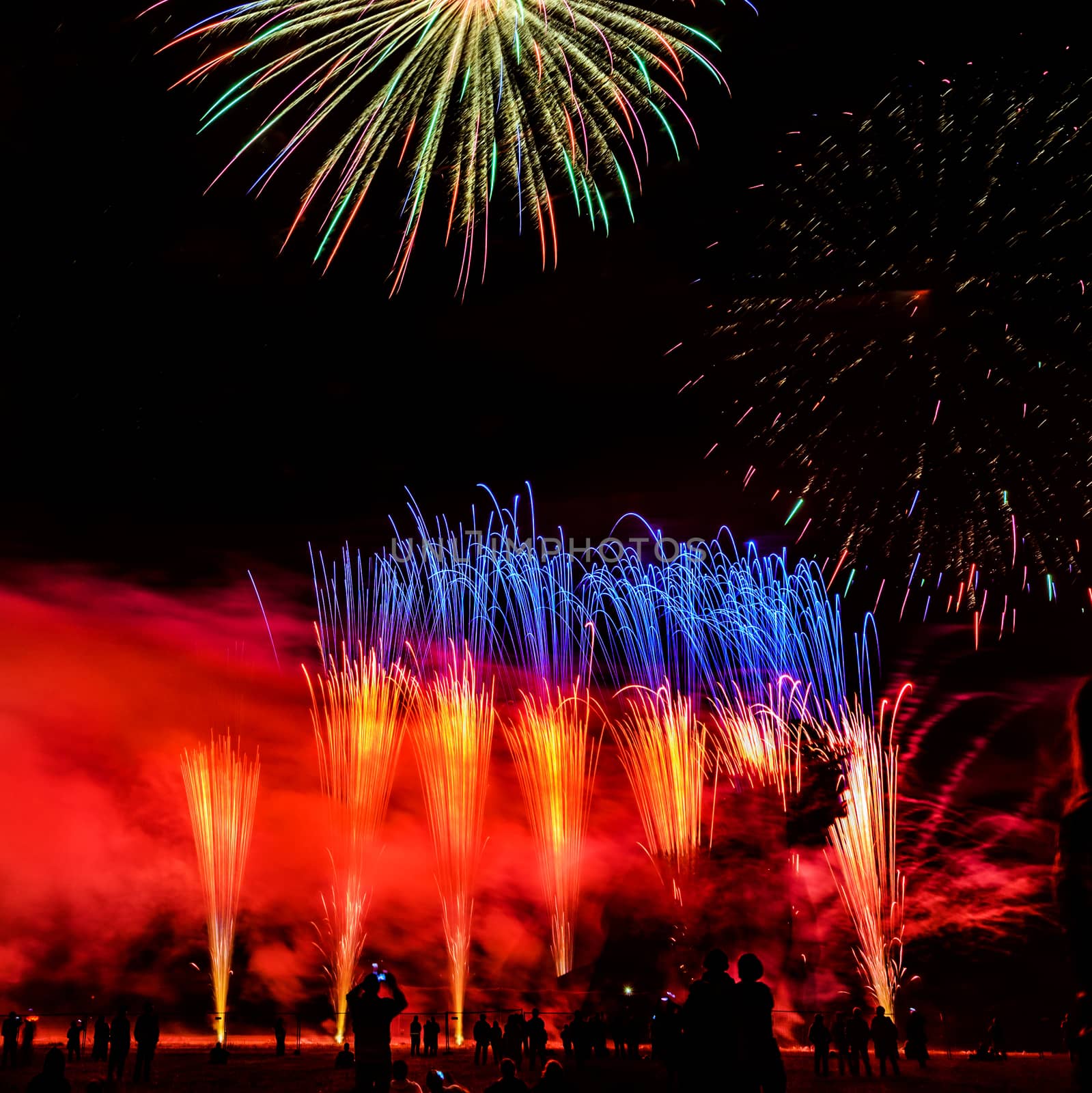 Colorful fireworks of various colors over night sky with spectators