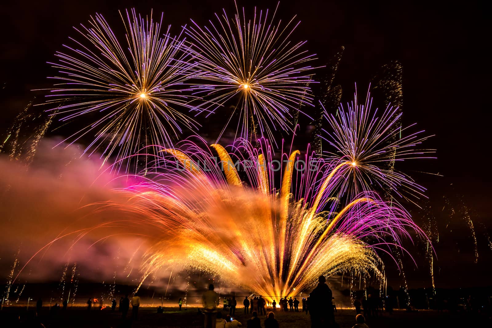 Colorful fireworks of various colors over night sky with spectators