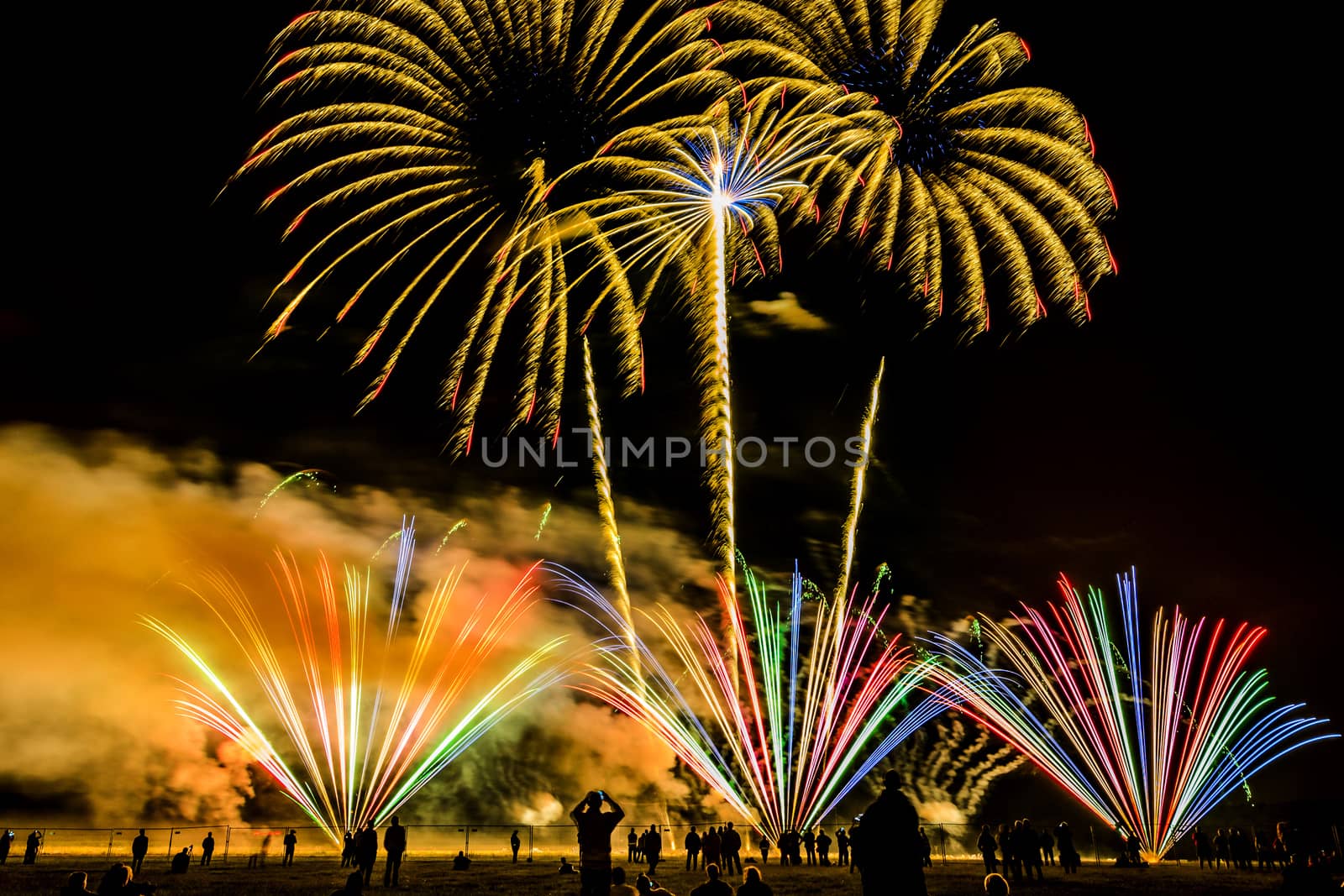 Colorful fireworks of various colors over night sky with spectators