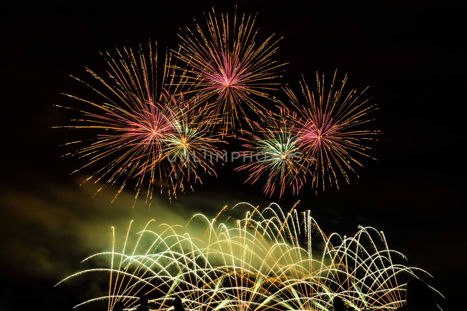 Colorful fireworks of various colors over night sky with spectators