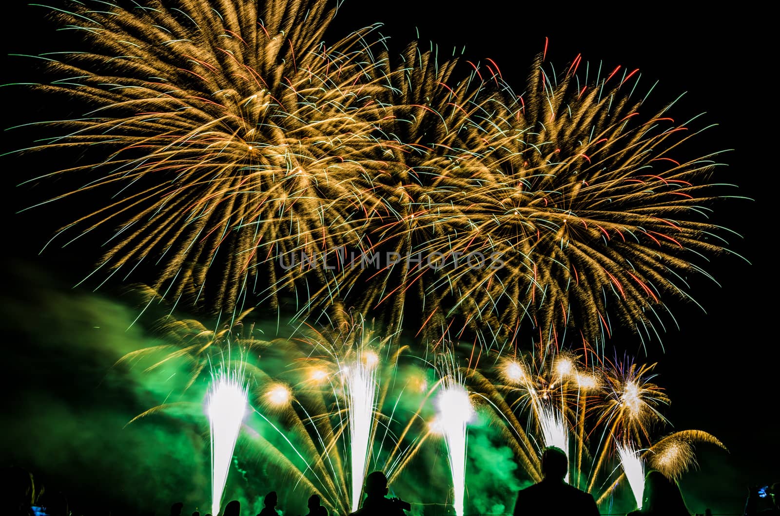 Colorful fireworks of various colors over night sky with spectators