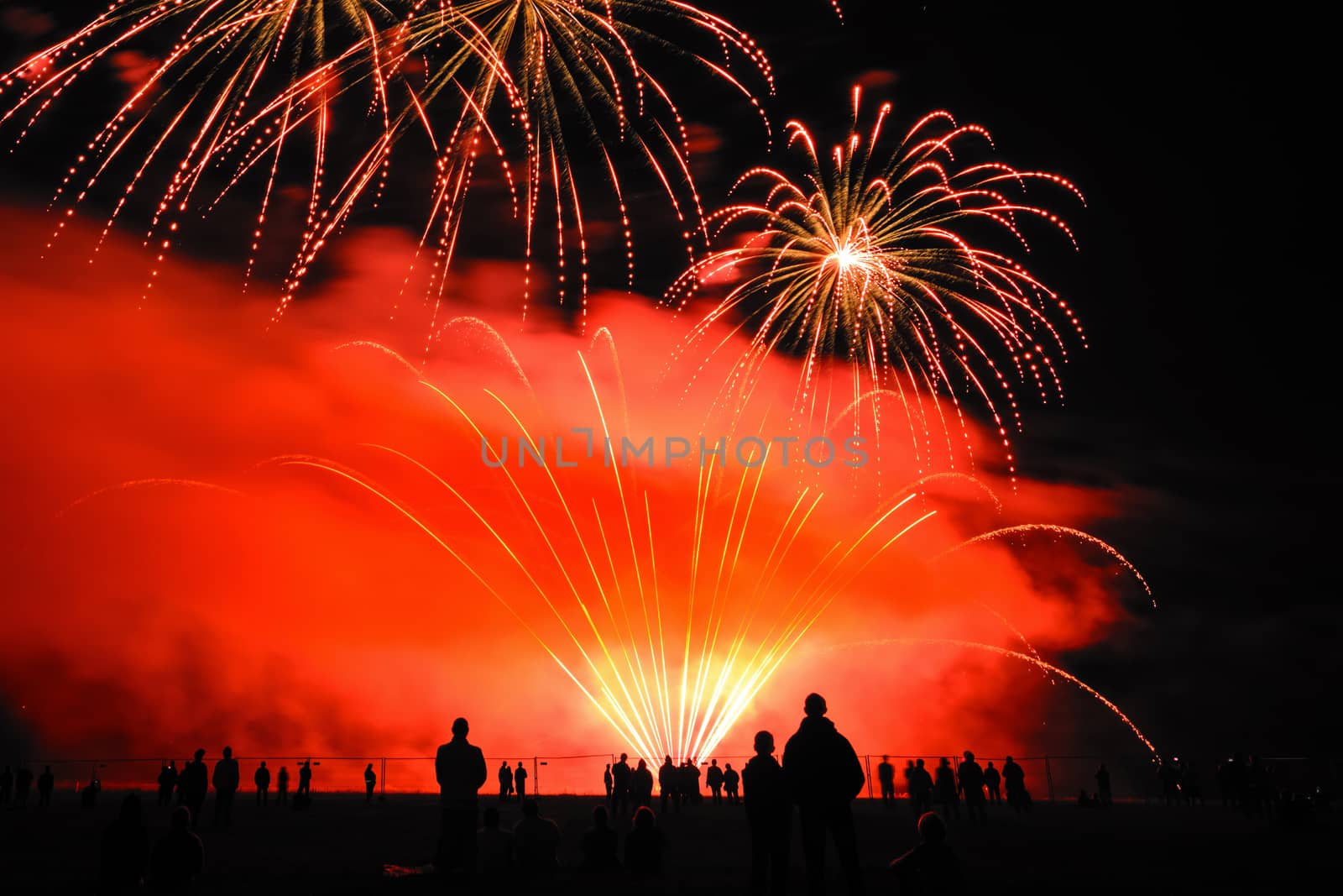 Colorful fireworks of various colors over night sky with spectators