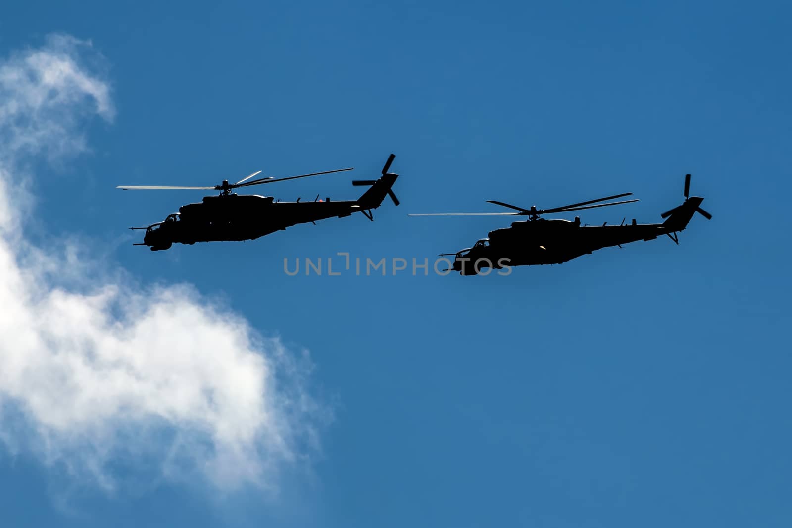 Two combat helicopters silhouettes flying in formation by Attila