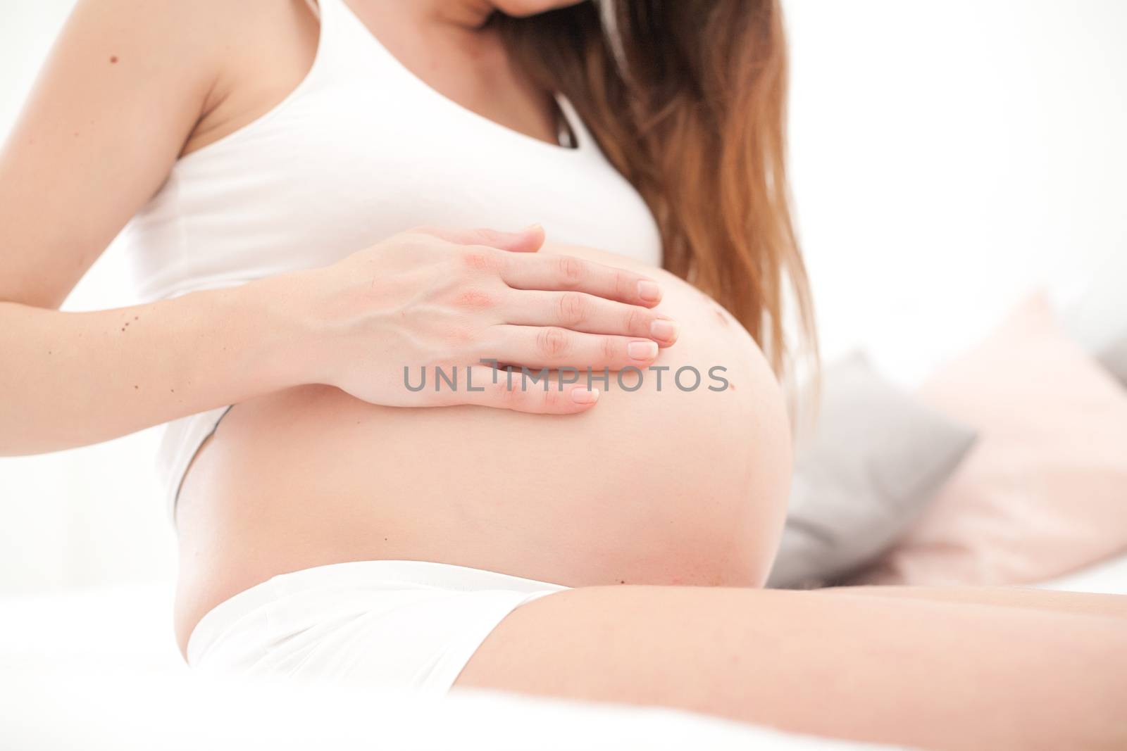Young new mother is sitting on a bed