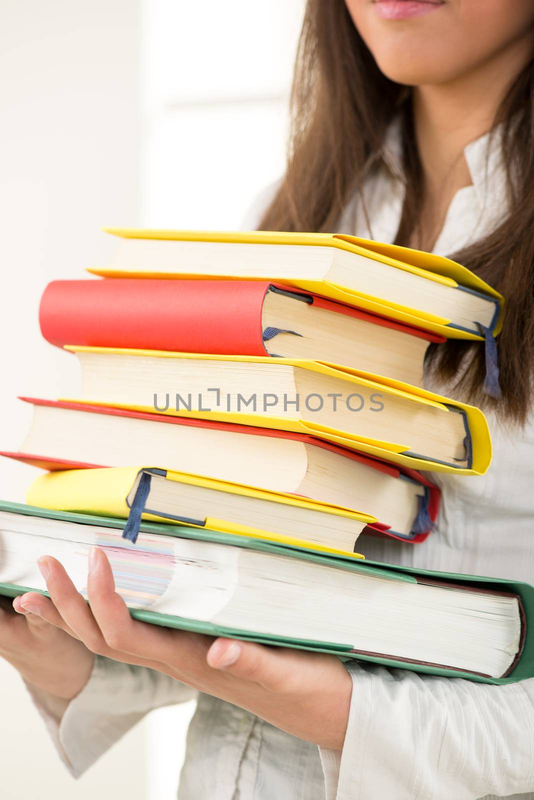 Unknown beautiful teenage girl holding many Colorful books 