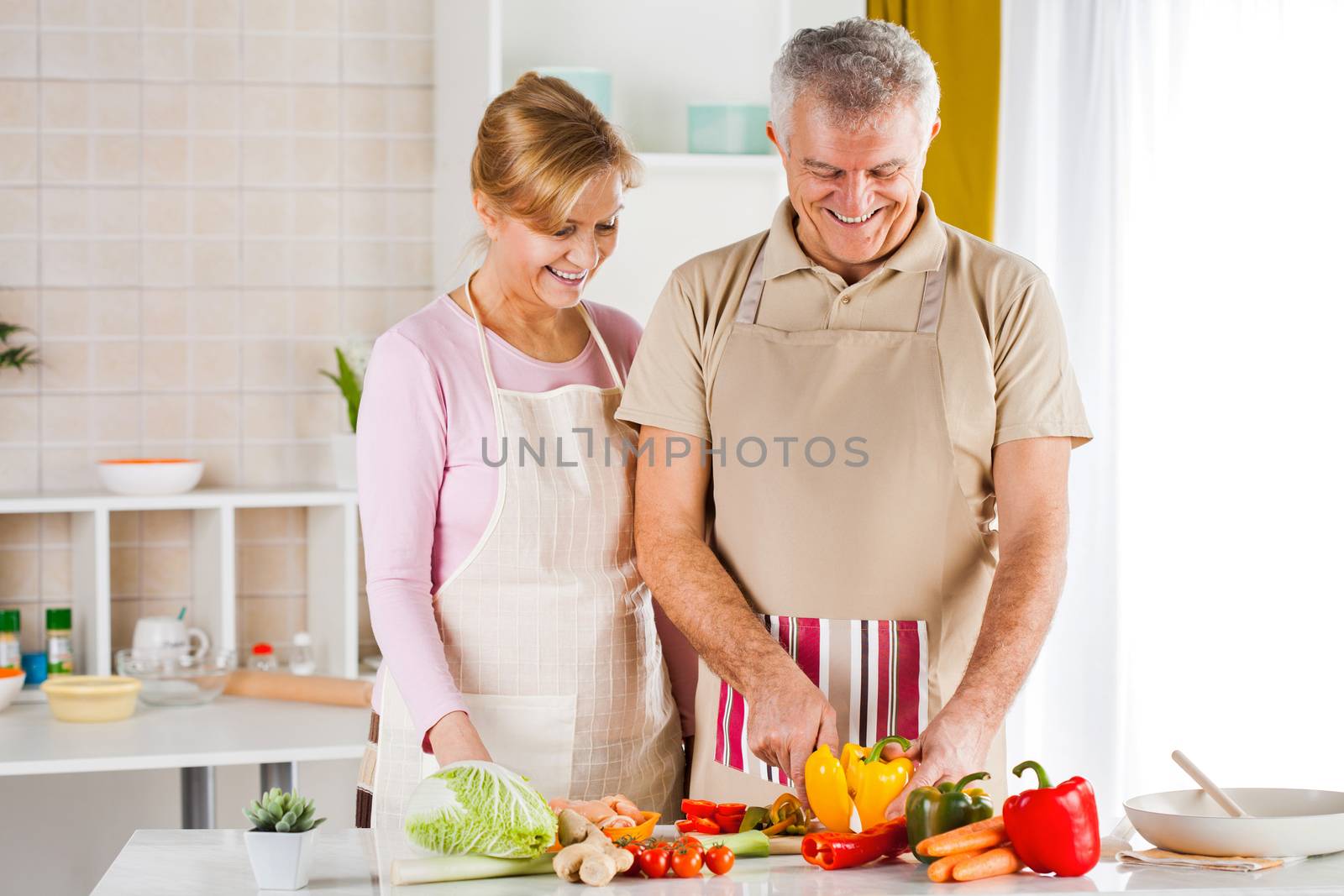 Happy Senior Couple cutting yellow peppers in the kitchen