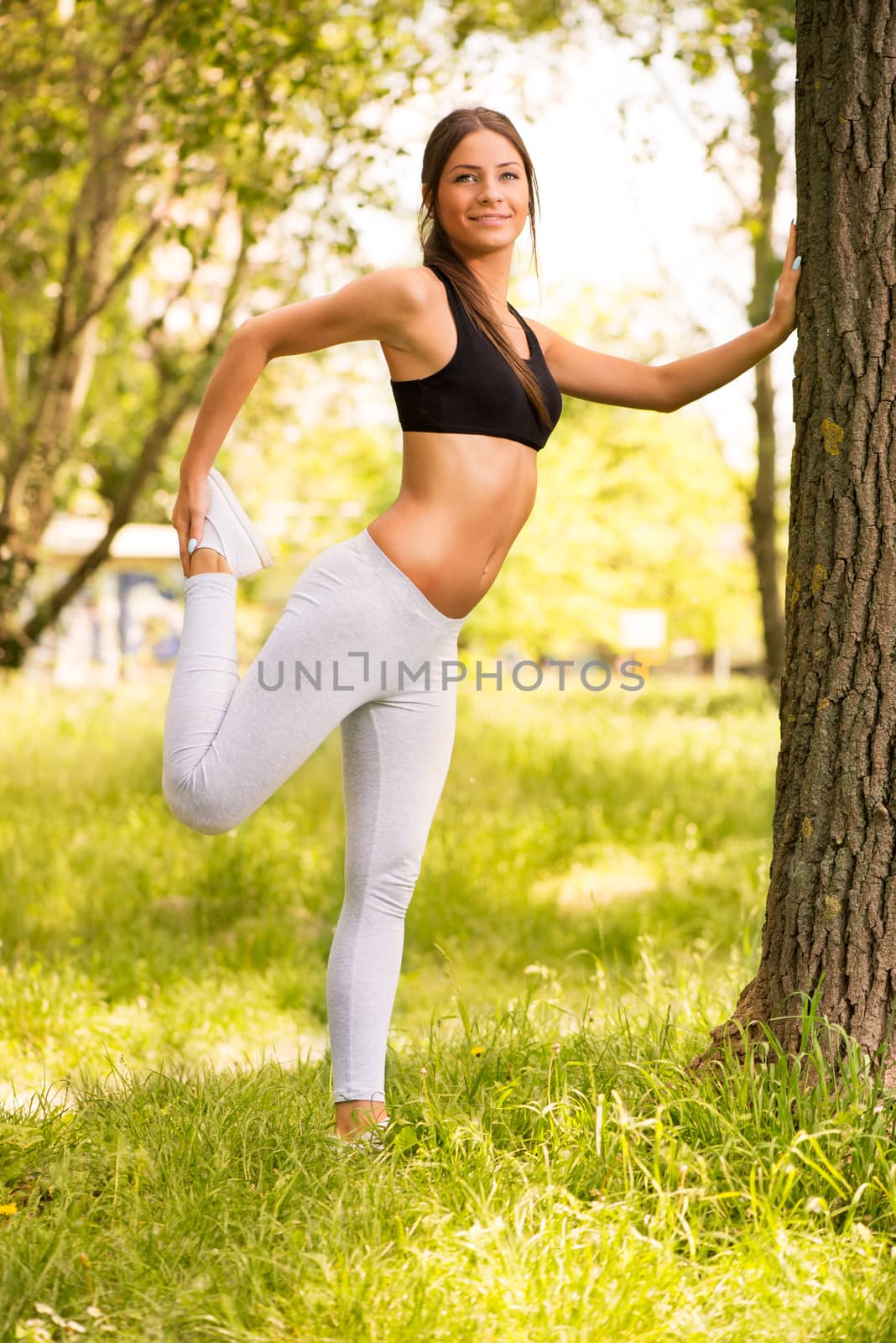Happy young beautiful woman stretching in the park