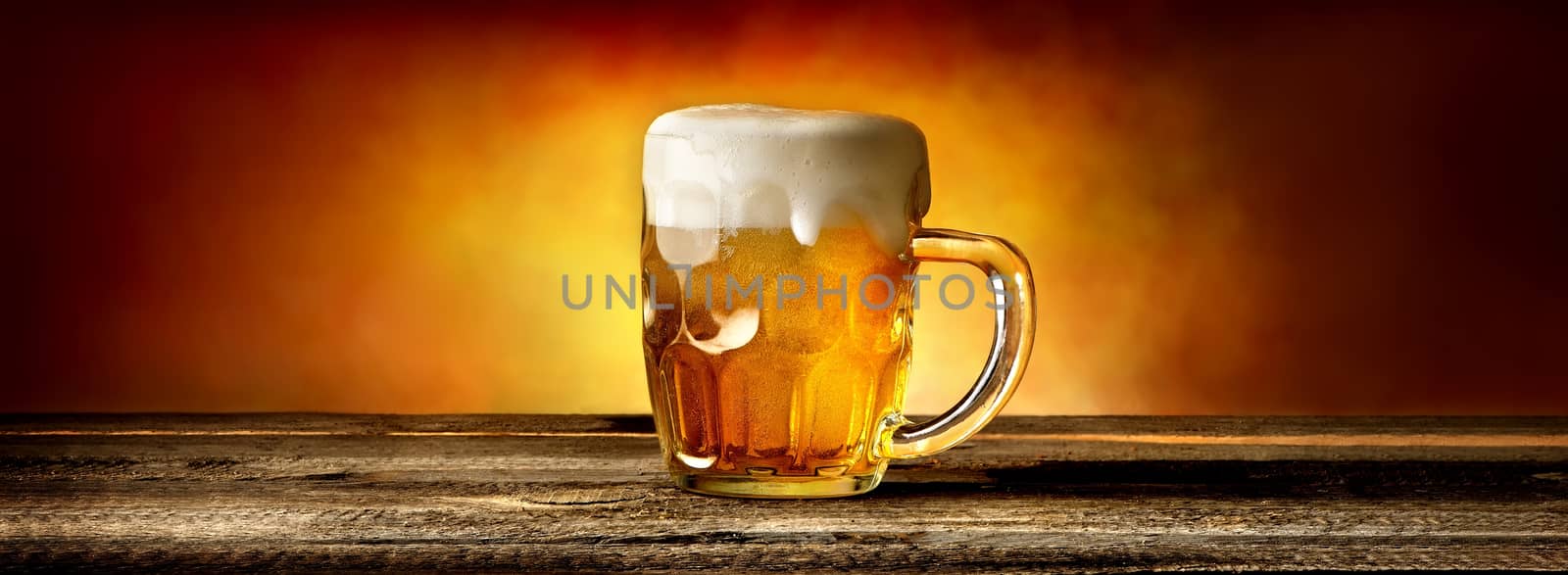 Light beer in glass mug on wooden table