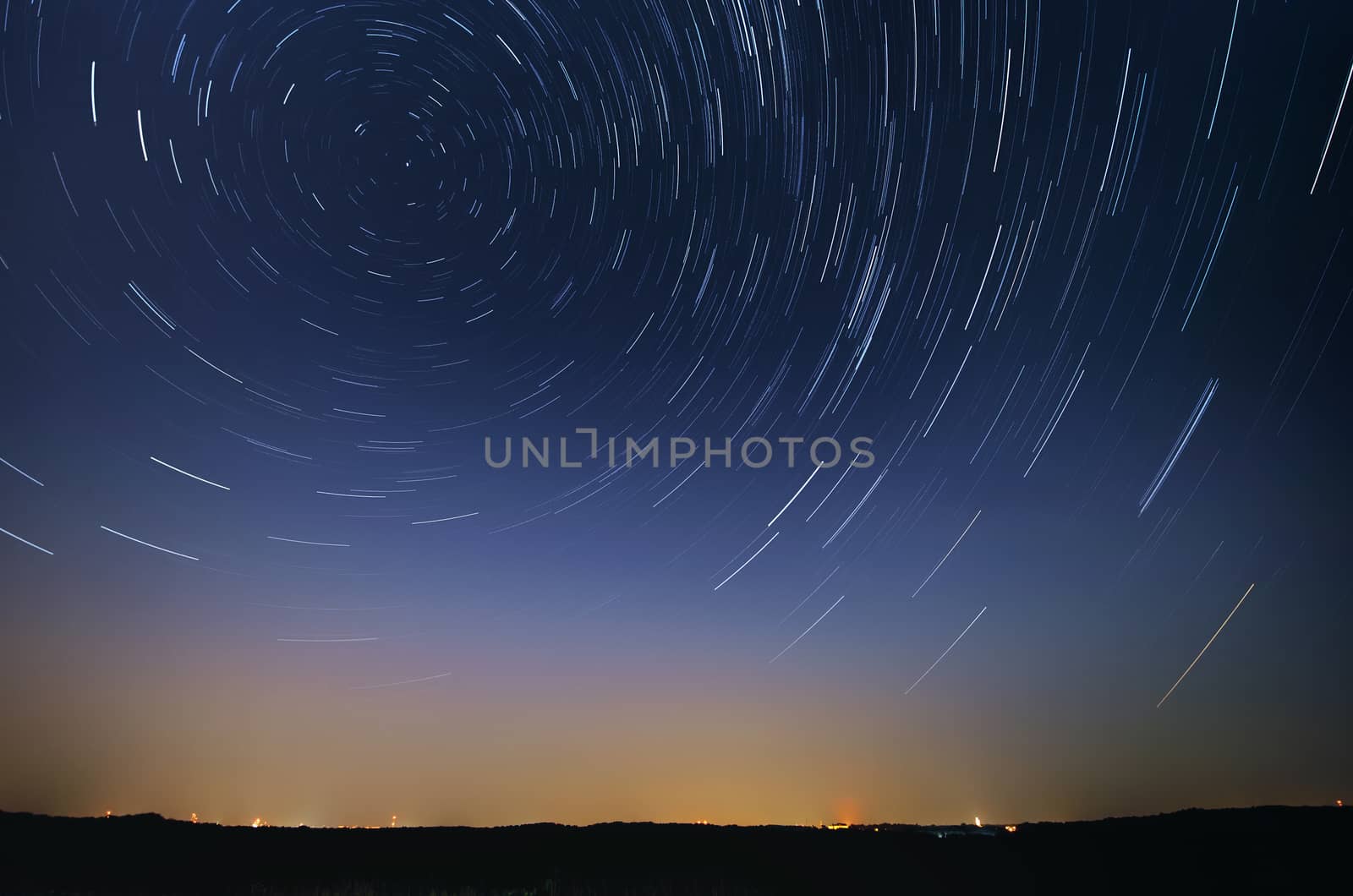 Startrail landscape of moving stars in night sky over the city by Attila