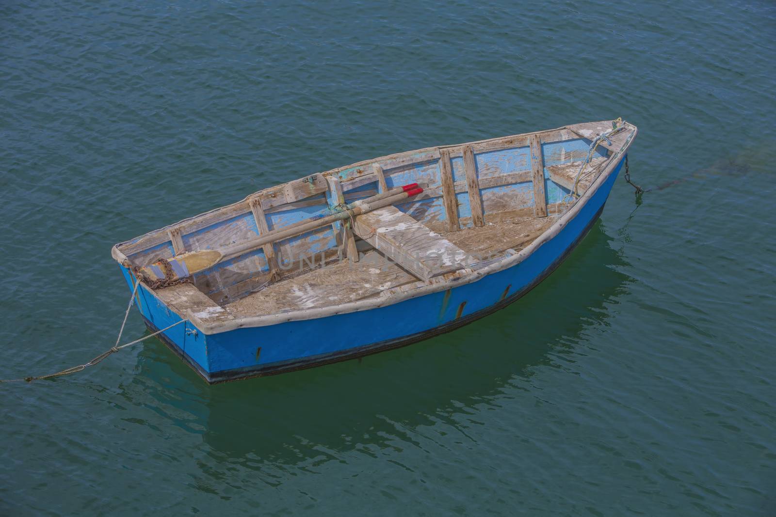 Colorful weathered rowboat anchored in shallow ocean water