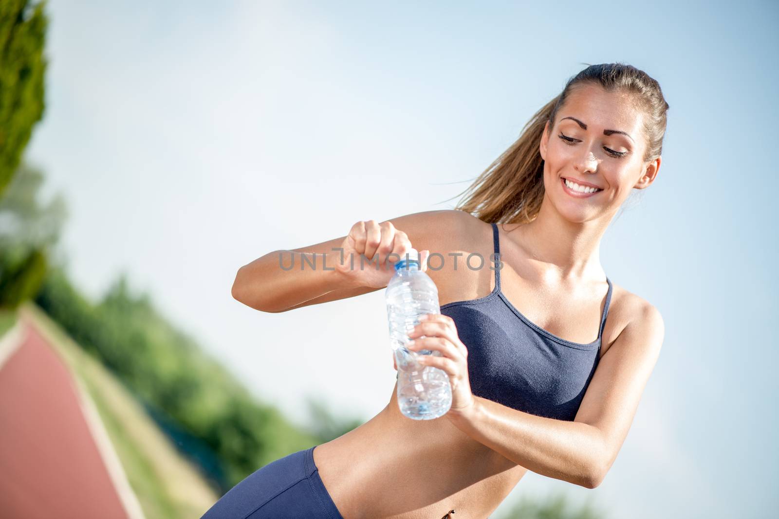 Beautiful young woman holding water bottle after training. 