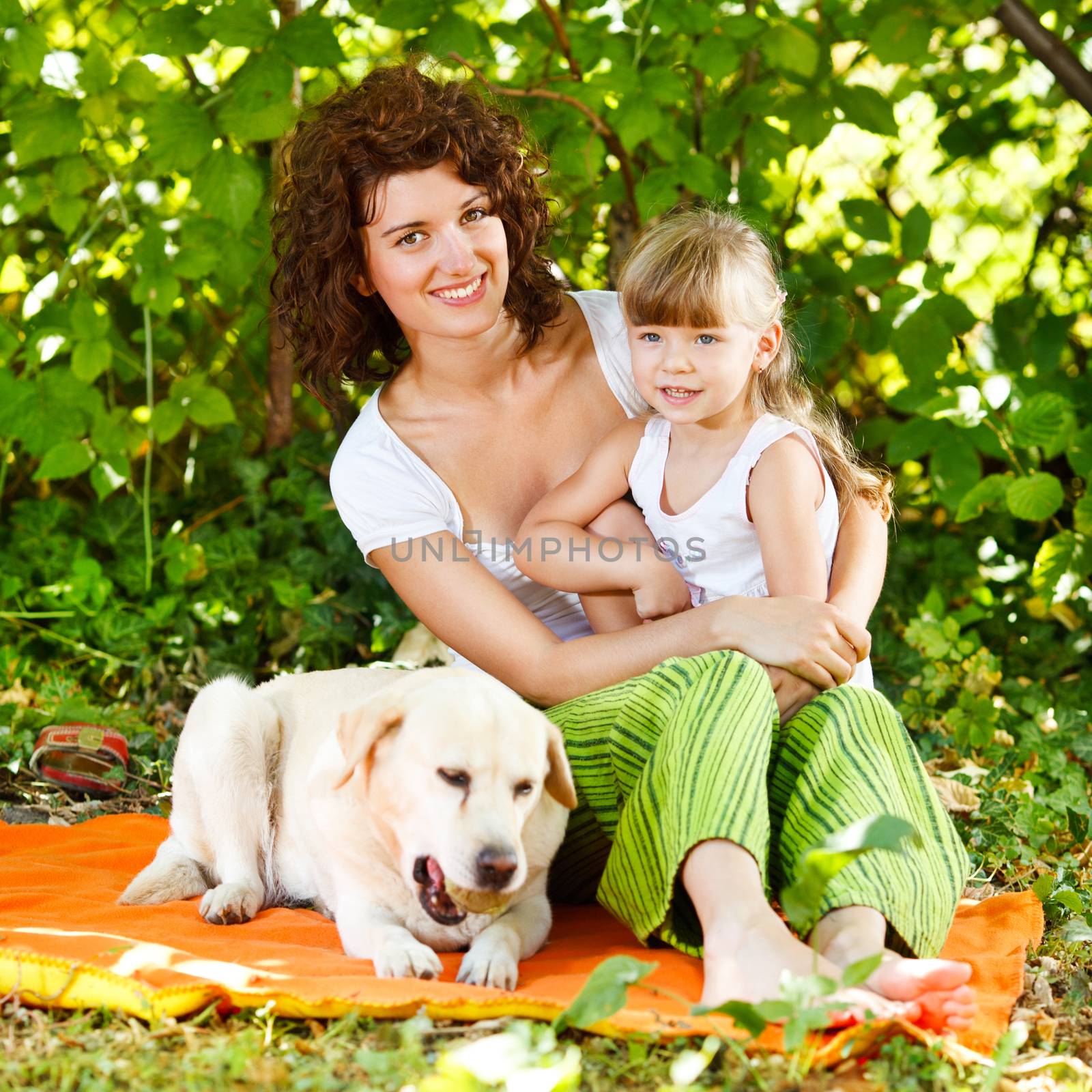 Beautiful mother and daughter relaxing in nature with their dog