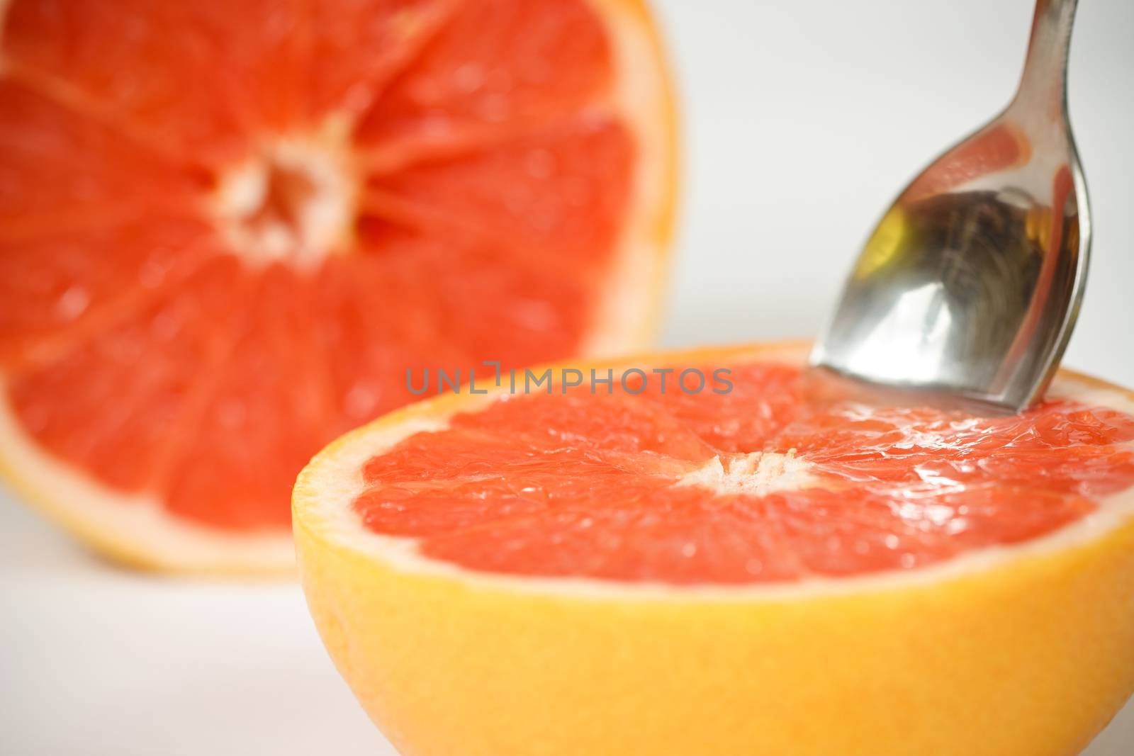 Halved red grapefruit with spoon