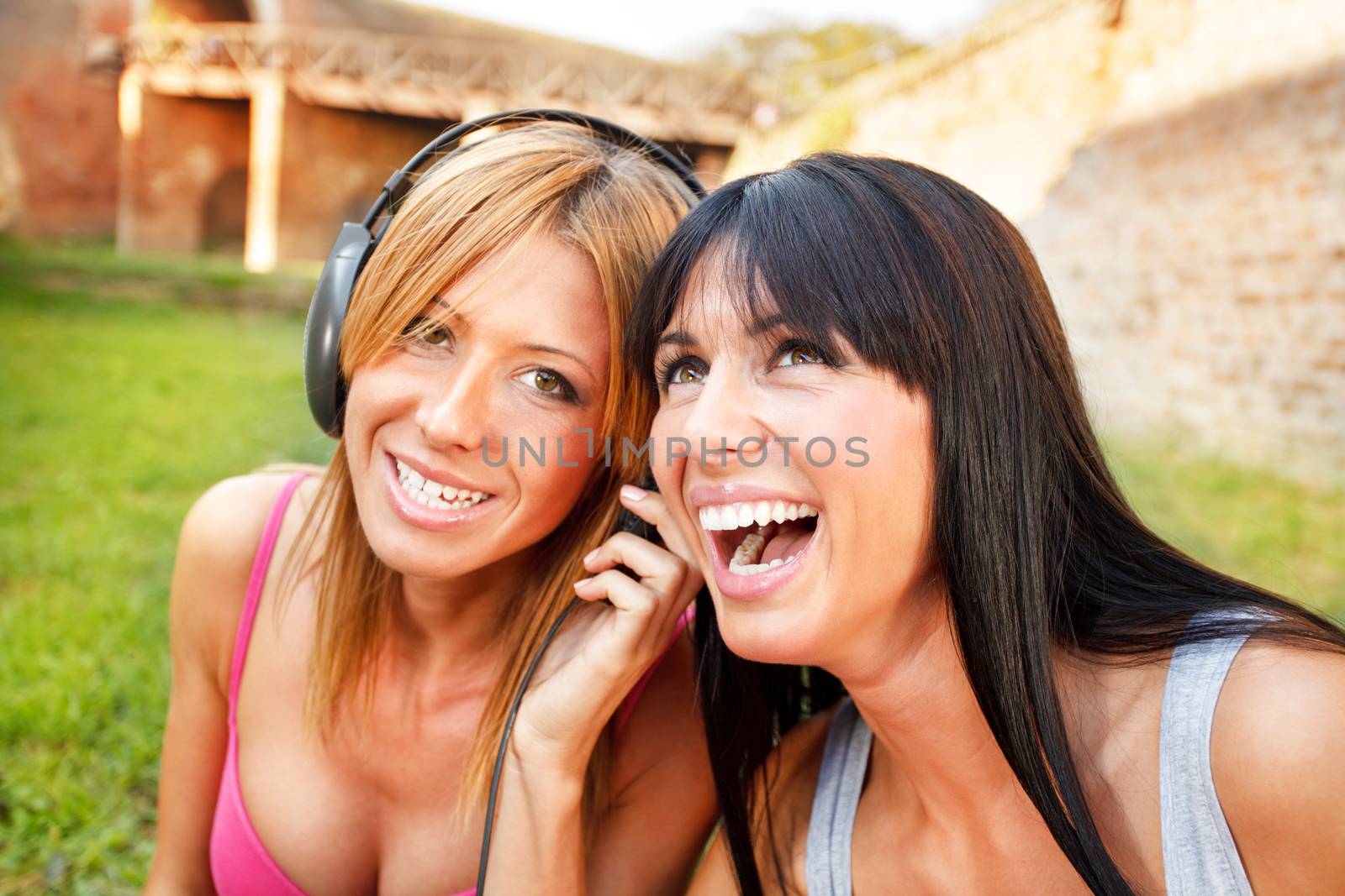 Close-up of two young beautiful girl listening music outdoor