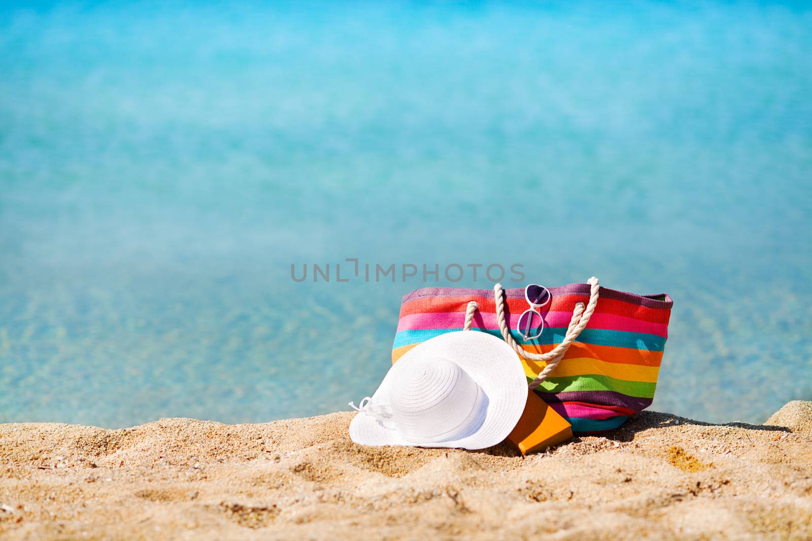 Multi Colored bag and white hat on the beach