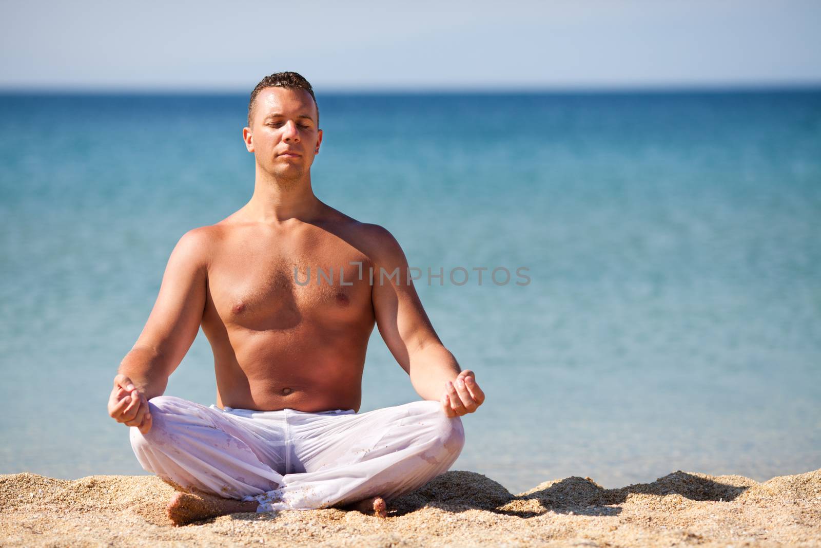 Young man meditating on the beach