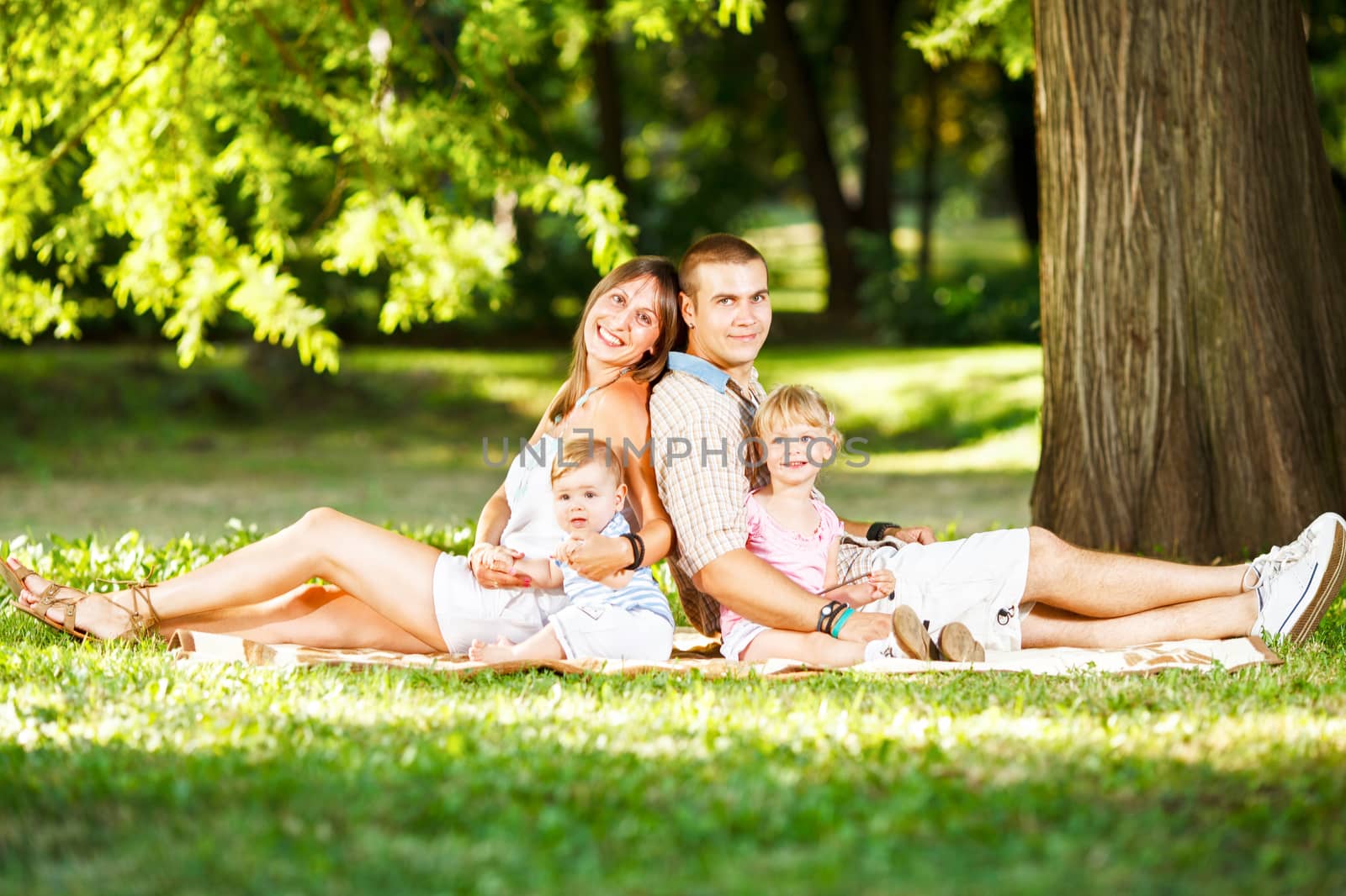 Beautiful happy family resting in the park. Looking at camera