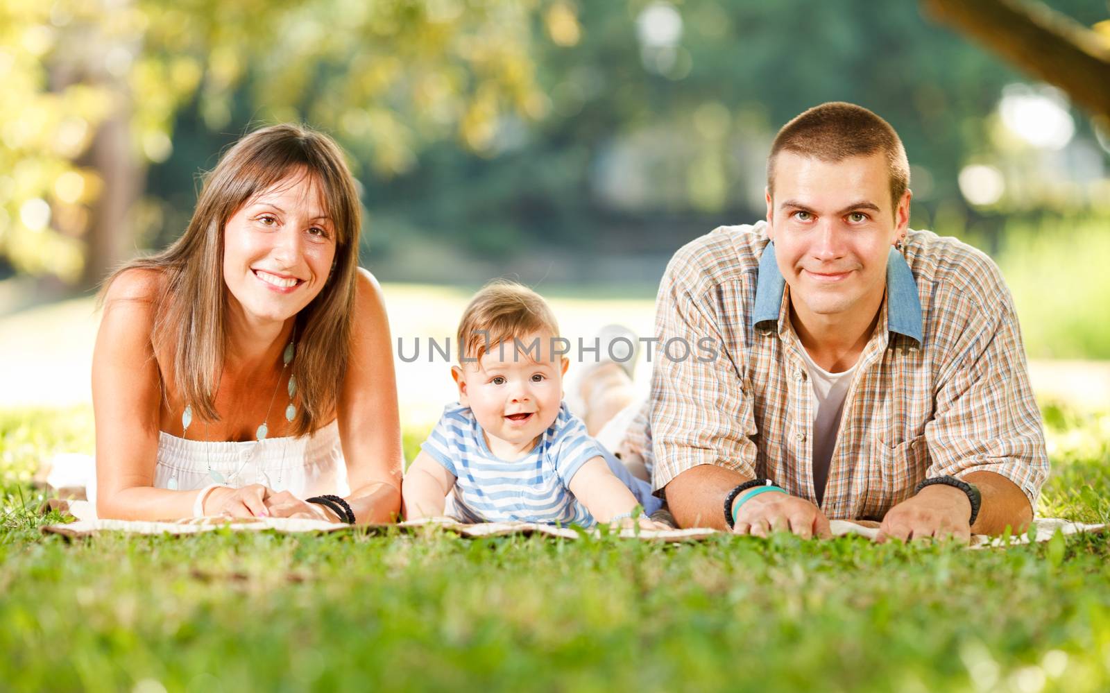 Beautiful happy family lie on the grass in park