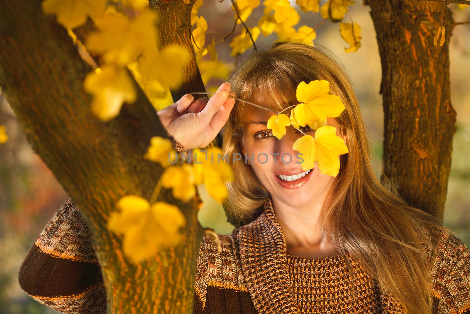 Beautiful women are hidden behind the leaves in autumn